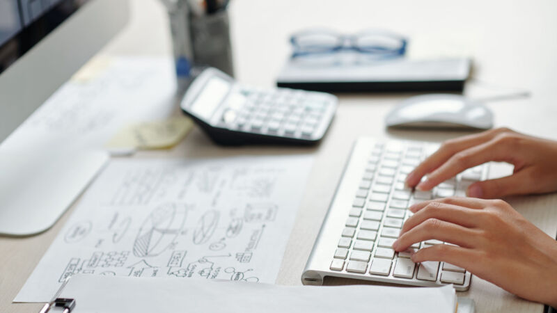 Hands of businesswoman working on computer at office desk, selective focus